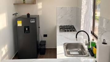 A compact kitchen with a refrigerator, sink, and stove.