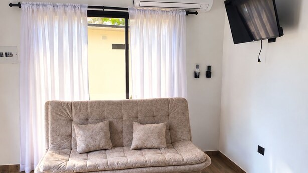 Un salon moderne avec un canapé, une table basse et un téléviseur à écran plat fixé au mur.