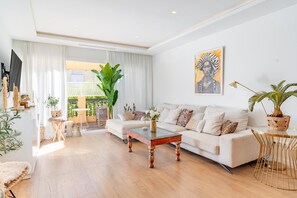 A modern living room with a sofa, coffee table, and potted plants. - GuestReady - Marbella Park (Marbella)