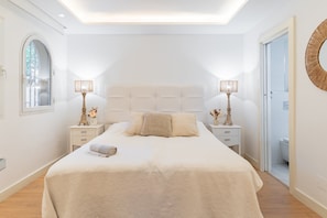 A bedroom with a large bed, two bedside tables, a window, and a door. - GuestReady - Marbella Park (Marbella)
