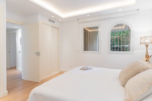A bedroom with a bed, a window with a view of greenery, a door, and a lamp. - GuestReady - Marbella Park (Marbella)