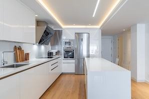A modern kitchen with white cabinetry, stainless steel appliances, and a central island. - GuestReady - Marbella Park (Marbella)