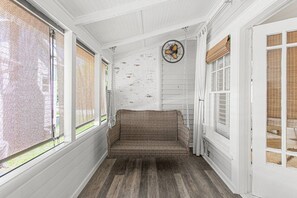 Eine überdachte Veranda mit einem Korbsessel, weißen Wänden und einem Deckenventilator.