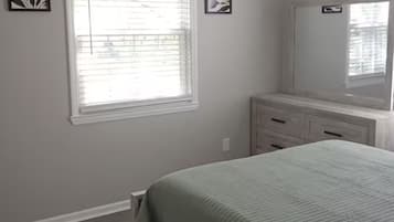 A bedroom with a bed, a ceiling fan, a window with blinds, and a dresser.