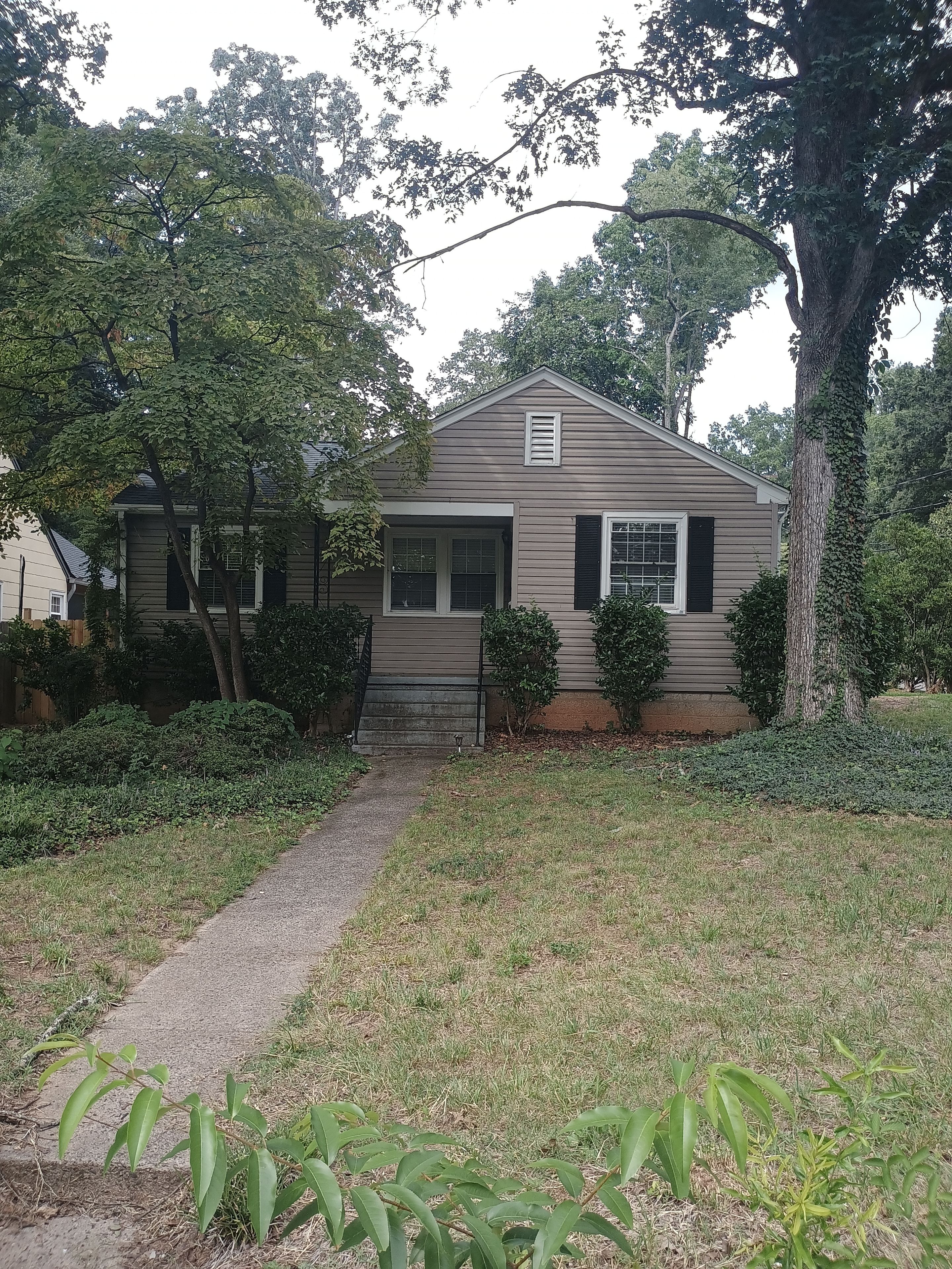 A single-story house with a front porch, a small front yard, and a pathway leading to the entrance.