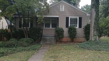A single-story house with a front porch, a small front yard, and a pathway leading to the entrance.