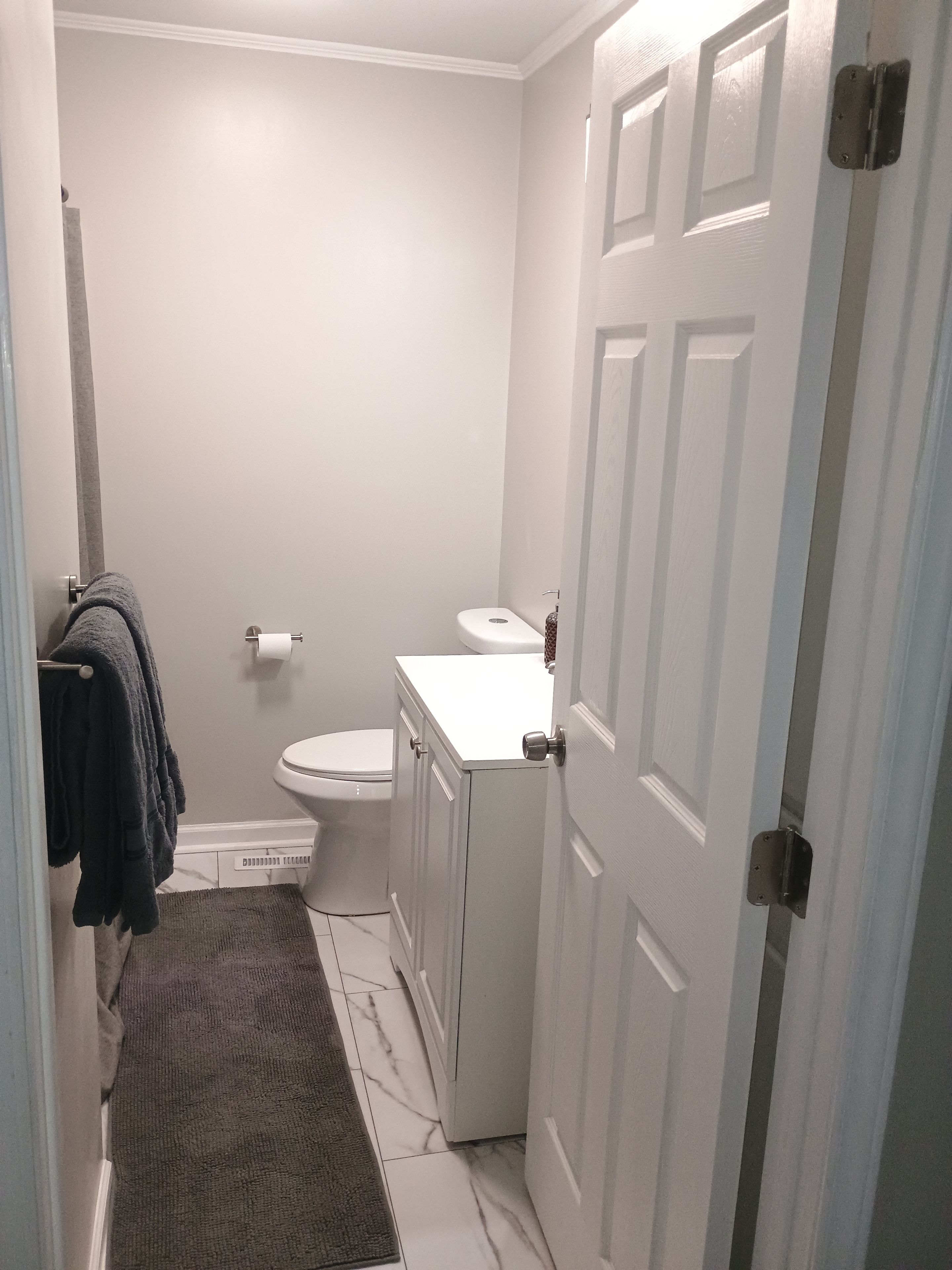A bathroom with a toilet, sink, and a towel rack with towels.