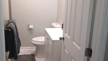 A bathroom with a toilet, sink, and a towel rack with towels.