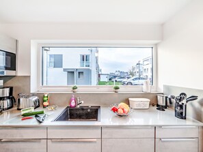 Een moderne keuken met een groot raam, een spoelbak en diverse apparaten.