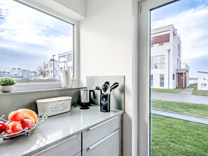 A modern kitchen with a large window, a coffee maker, and a fruit bowl. - Apartment Ahoi by Interhome (Hasselberg)