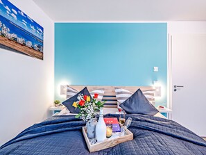 Een hotelkamer met een bed, nachtkastje, wand met een schilderij en een deur.