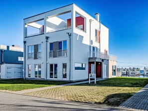 A modern multi-story residential building with a flat roof, large windows, and a visible balcony. - Apartment Ahoi by Interhome (Hasselberg)