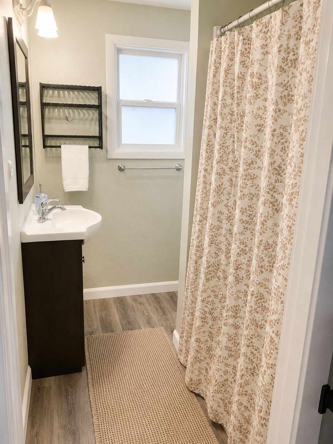 A bathroom with a sink, mirror, window, and shower curtain.