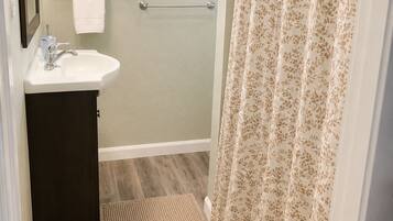 A bathroom with a sink, mirror, window, and shower curtain.