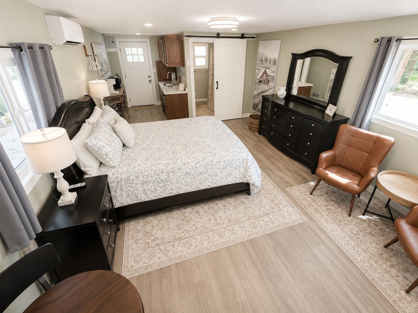 A bedroom with a bed, bedside tables, a dresser, a chair, and a small table.