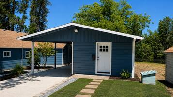 A single-story building with a covered porch, a door, and a small garden area with stepping stones.