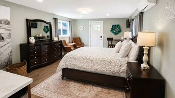 A bedroom with a bed, dresser, chair, and a desk with a lamp.