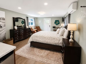 Quarto com cama, cômoda, cadeira e escrivaninha com abajur.