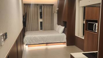 Una habitación de hotel moderna con cama, armario empotrado y kitchenette.