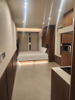 Una habitación de hotel moderna con cama, armario empotrado y kitchenette.