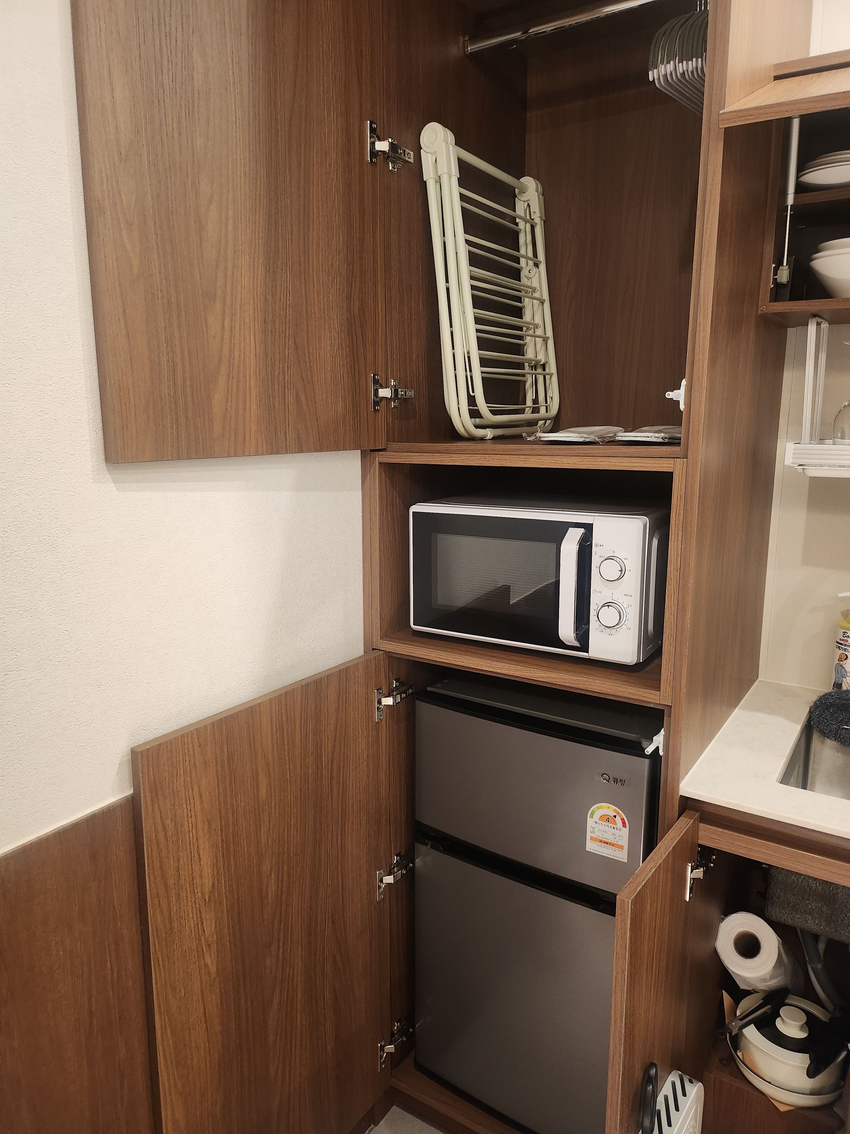 Een praktische keuken met een magnetron, een kleine koelkast en een droogrek.