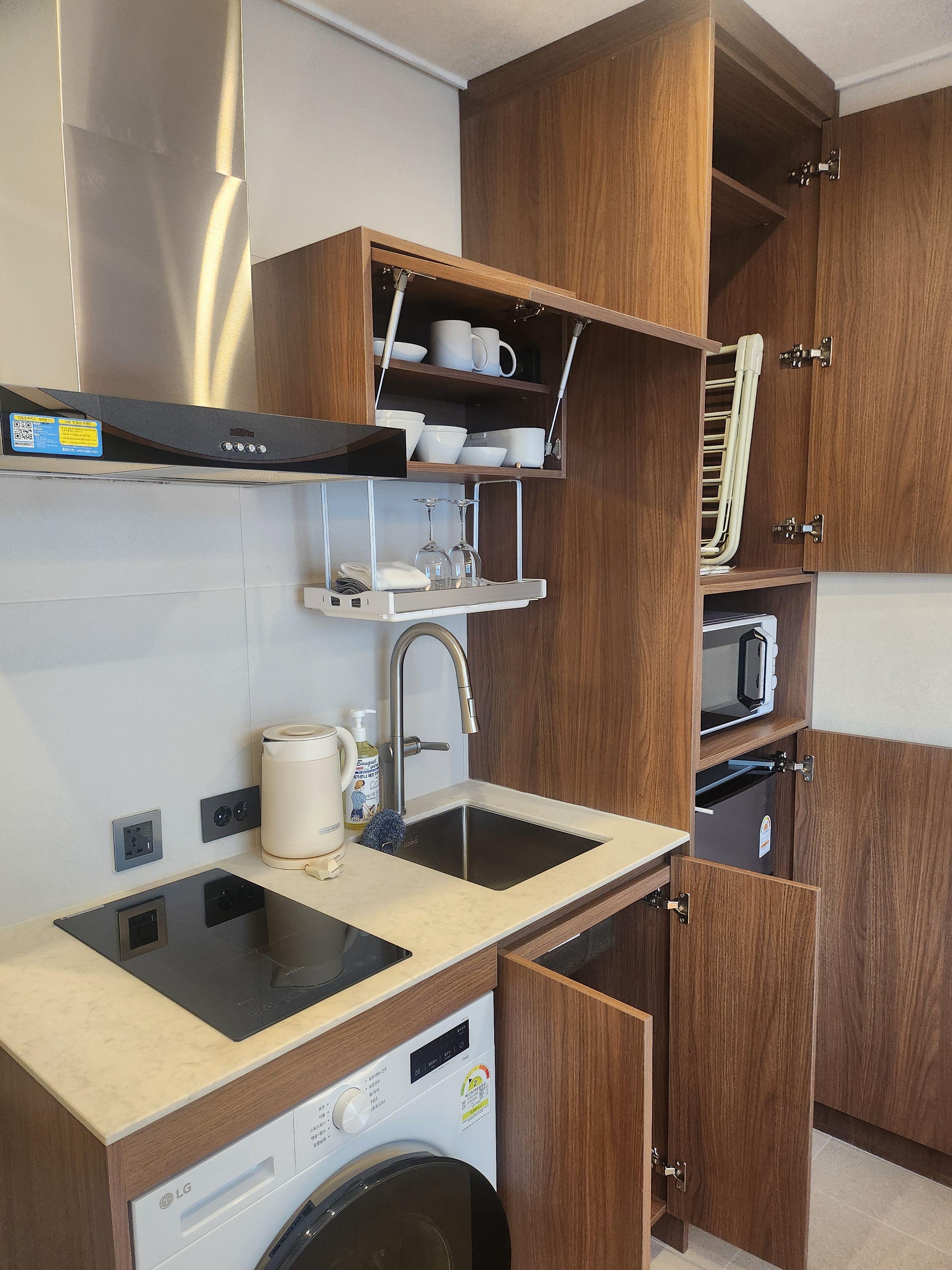 Een praktische keuken met een ingebouwde wasmachine, een magnetron en een spoelbak.