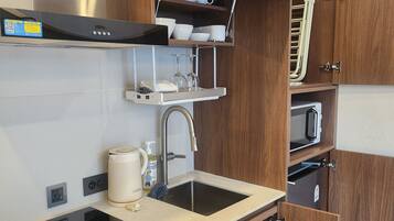 Een praktische keuken met een ingebouwde wasmachine, een magnetron en een spoelbak.