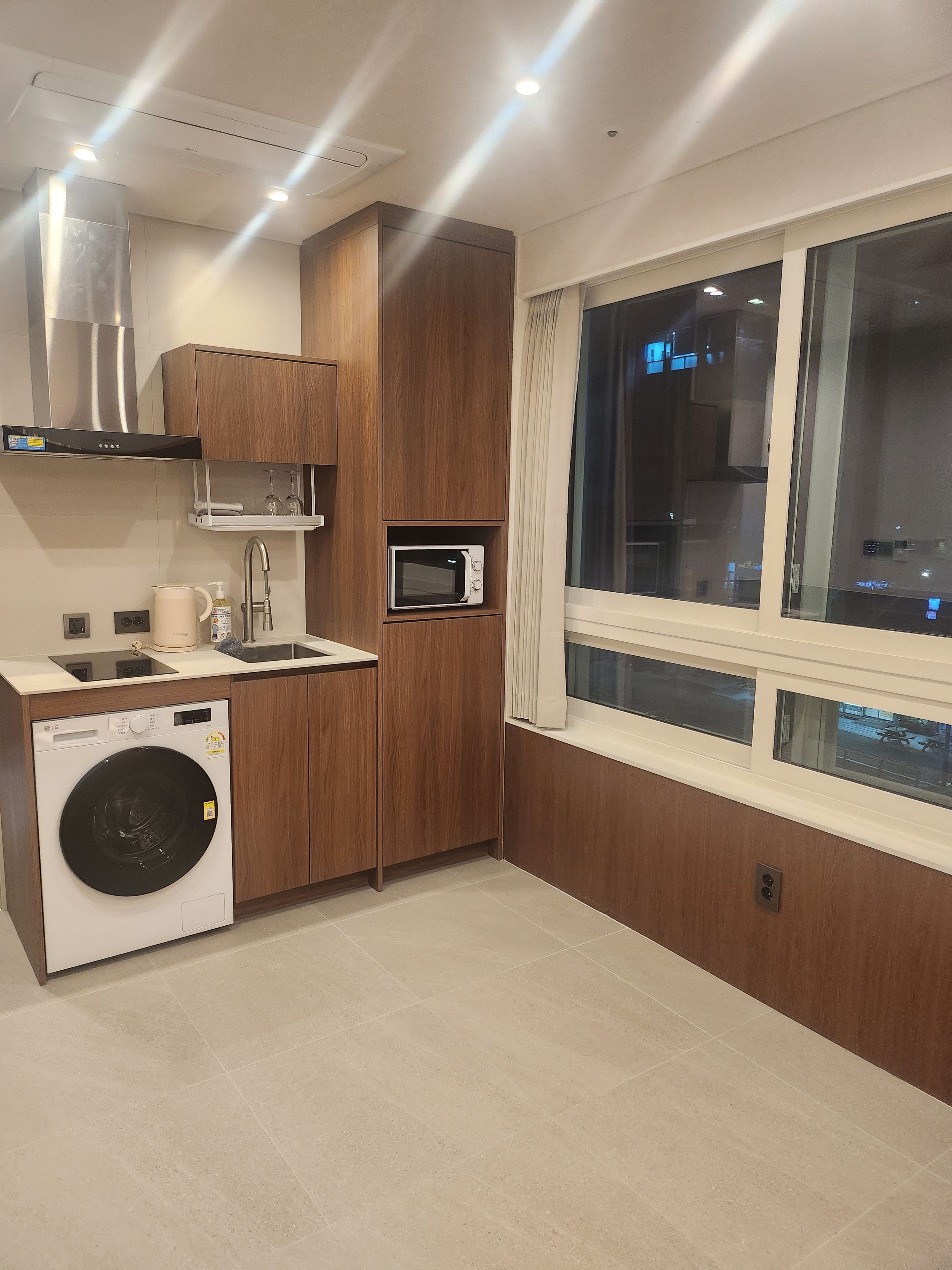 Una cocina compacta con lavadora, microondas y horno empotrado.