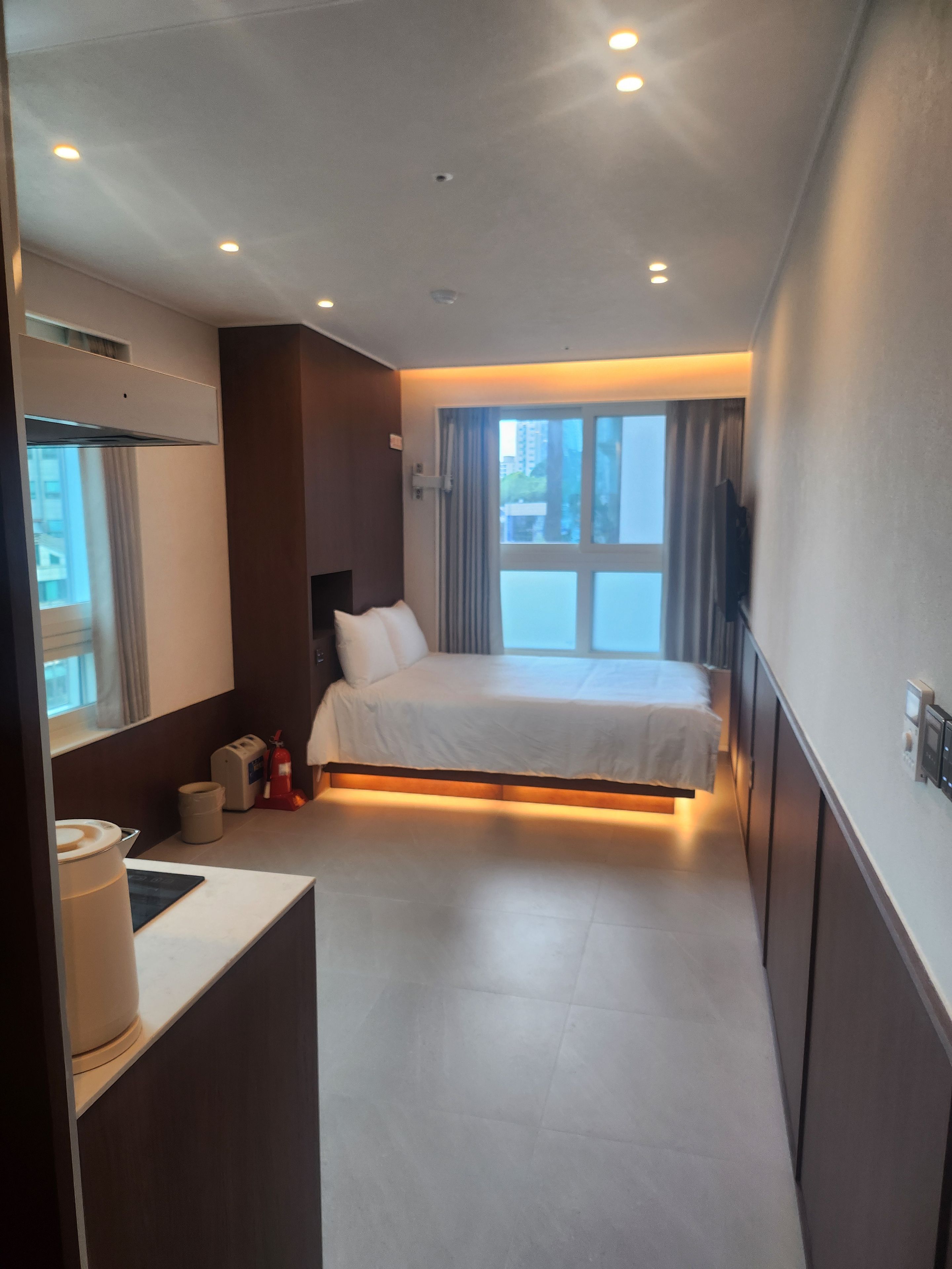 Een moderne hotelkamer met een groot bed, een nachtkastje, een spiegel, een televisie en een raam met gordijnen.