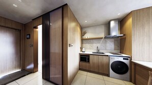Eine moderne Küche mit Holzschränken, einer eingebauten Mikrowelle und einer Waschmaschine.