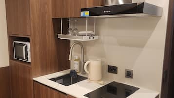 Een praktische keuken met houten kastjes, een roestvrijstalen afzuigkap, een magnetron, een koffiezetapparaat en een ingebouwde wasmachine.