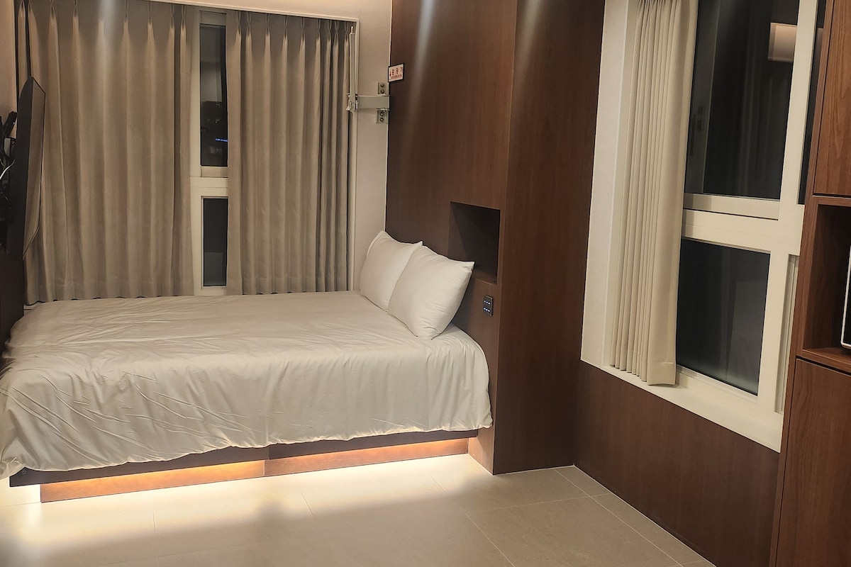Un dormitorio con cama, cortinas, una ventana y un cubo de basura.