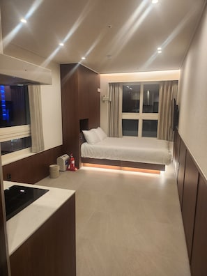 A modern hotel room with a bed, bedside table, and a built-in TV. - THE DH STAY (Seoul)