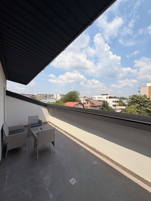 A balcony with wicker furniture and a clear view of the surrounding buildings and sky. - Cozy 1-bedroom apartment in northside Bucharest with AC and terrace (București)