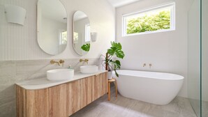 A modern bathroom with a freestanding bathtub, two sinks with gold faucets, and a large mirror above the vanity. - Mira Sol, Richmond Hosted by L'Abode Accommodation (Richmond)