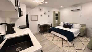 A modern bedroom with a bed, desk, and kitchenette. - Stadium Nest /king Bed/ pet friendly (Tampa)