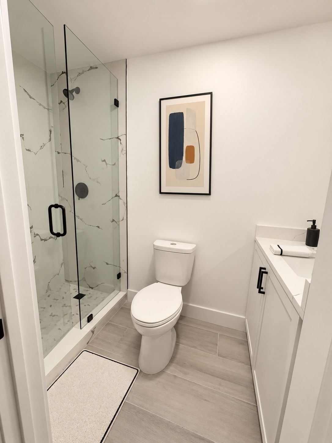 Un baño moderno con cabina de ducha de vidrio, inodoro y lavabo con encimera.