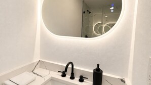 A modern bathroom with a white sink, a black faucet, a soap dispenser, and a large mirror with integrated lighting. - Stadium Nest /king Bed/ pet friendly (Tampa)