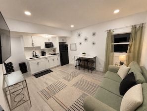 A modern kitchen with white cabinets, a black refrigerator, and a dining area with a table and chairs.