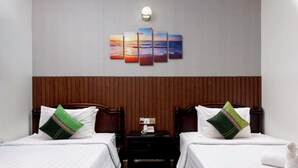 Une chambre d’hôtel avec deux lits, une table de chevet avec un téléphone et une œuvre d’art accrochée au mur au-dessus des lits.