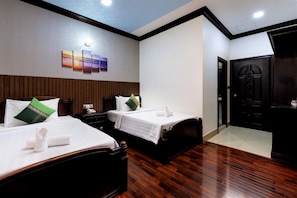 A hotel room with two beds, wooden flooring, a wall-mounted artwork, and a door. - Central Boutique (Siem Reap)