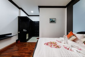 Ein Hotelzimmer mit einem Bett, einem Bild an der Wand, einem schwarzen Wandschrank und einem Holzboden.