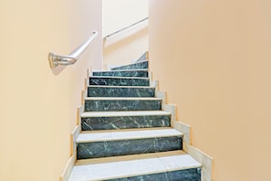 Una escalera con escalones de mármol y barandilla de metal.