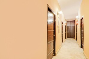 A corridor with wooden doors, a fire extinguisher, and a light fixture on the wall.