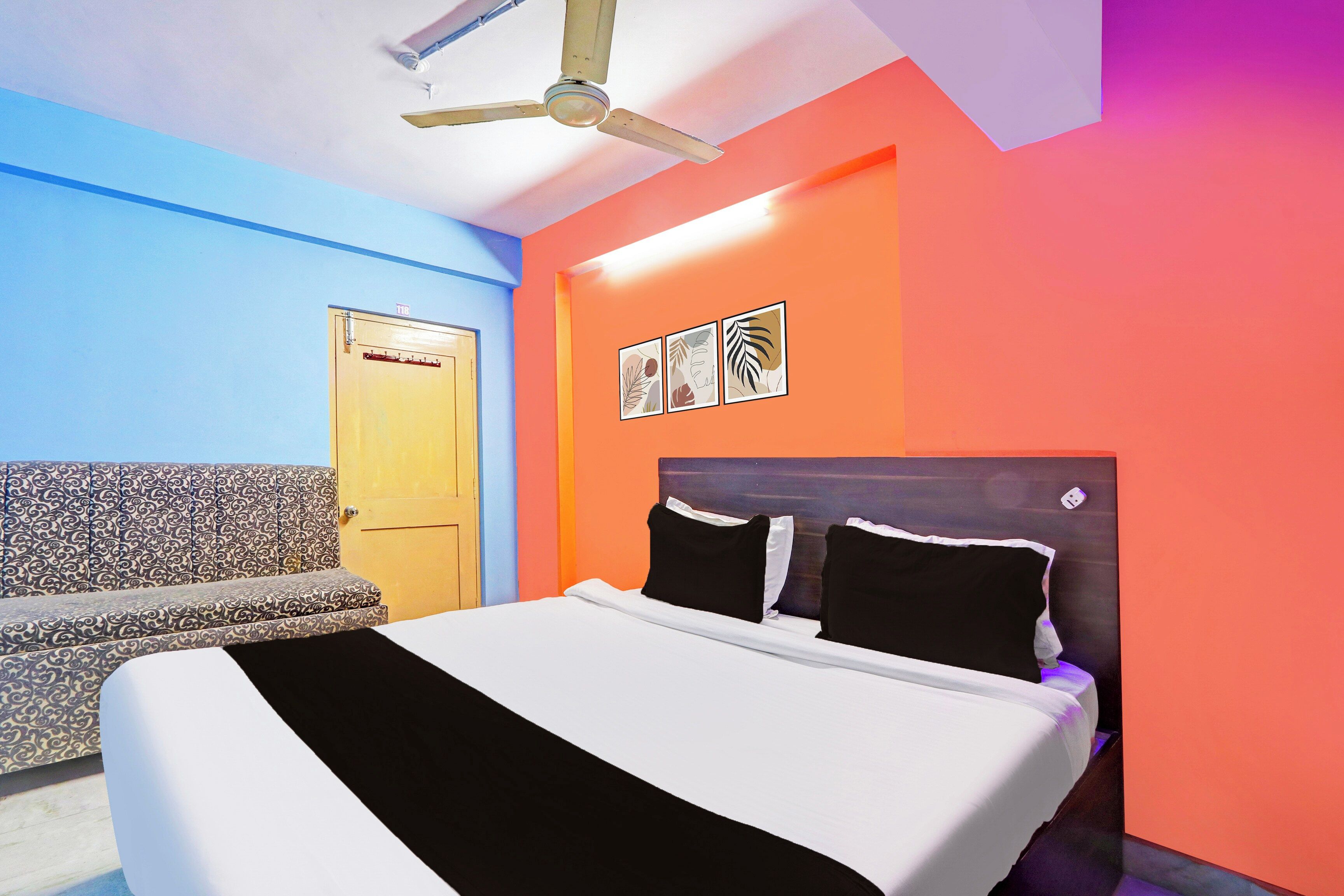 Una habitación con cama, sofá, ventilador de techo y una puerta.