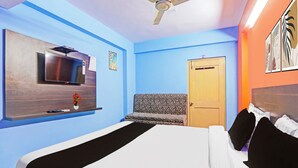 Une chambre d’hôtel avec un lit, une télévision, un ventilateur de plafond et une porte.