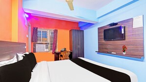 Une chambre d’hôtel avec un lit, une télévision, un bureau et une fenêtre avec des rideaux.