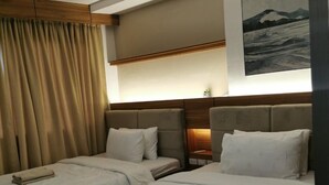 Habitació d'hotel amb dos llits, un capçal de llit de fusta, un quadre a la paret i una finestra amb cortines.