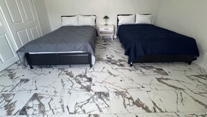 Una camera da letto con due letti, una porta bianca e un comodino con una lampada.