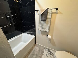 Un baño con bañera, inodoro y toallero.